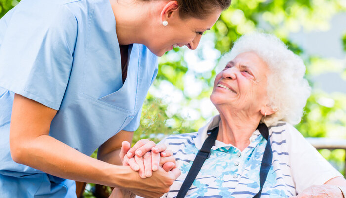 Pflegerin lacht mit einer Seniorin