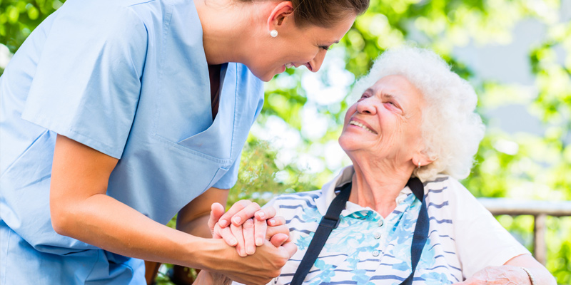 Pflegerin lacht mit einer Seniorin